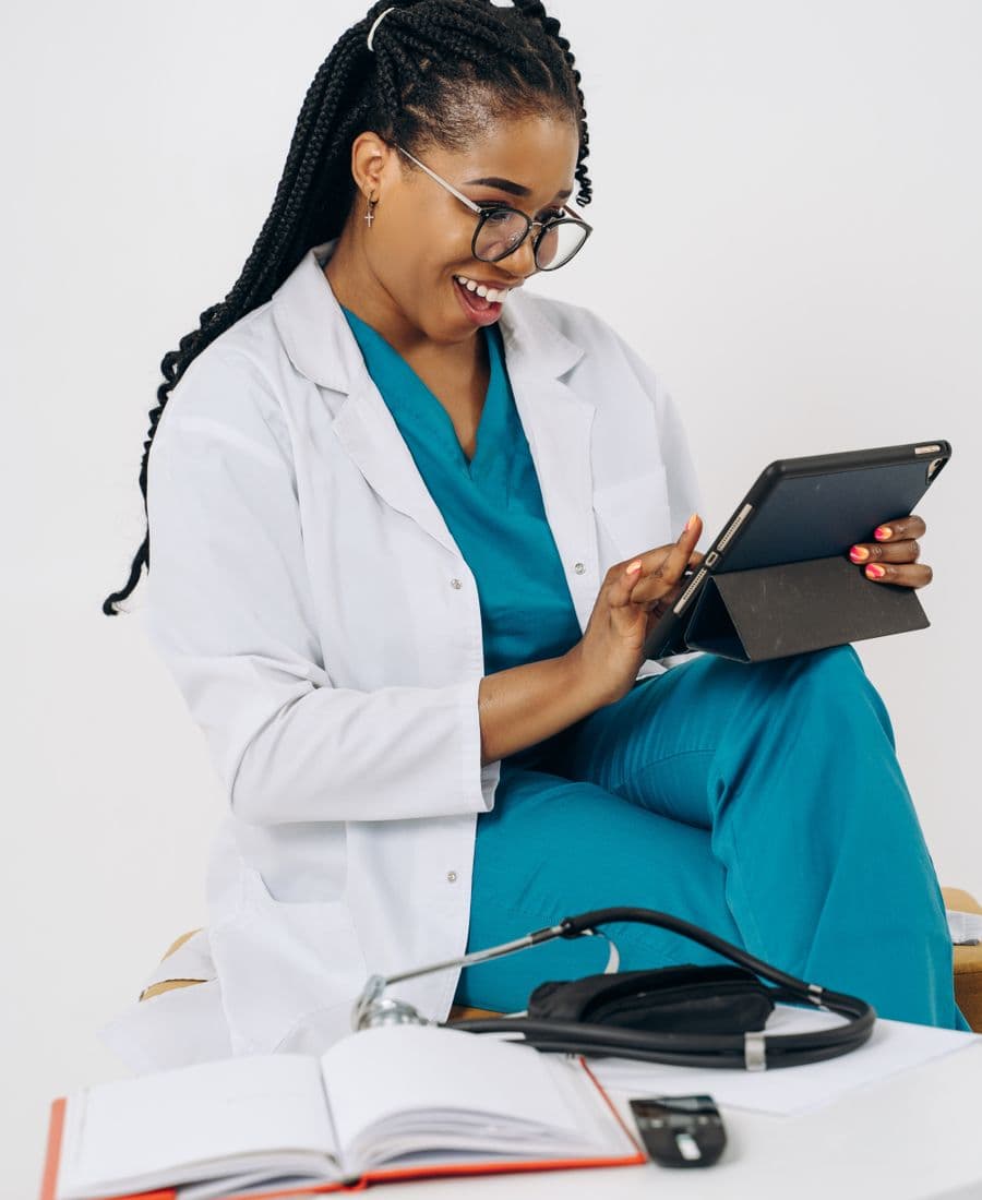 Smiling clinician in scrubs using a tablet